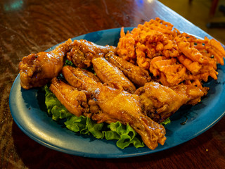 Close up shot of a plate of deep fried chicken wings and fries