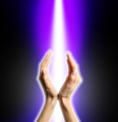 Female hands and beam of shining energy on dark background