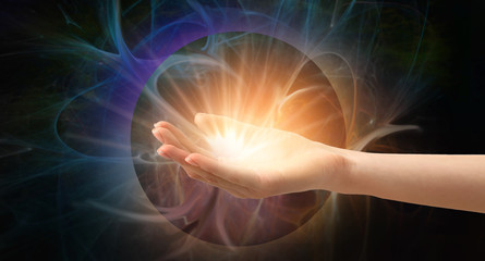 Female hand with shining energy on dark background