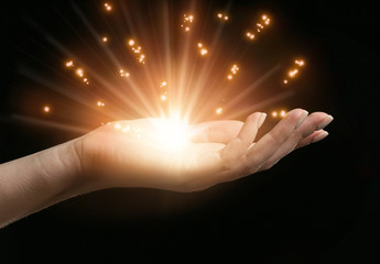 Female hand with shining energy on dark background