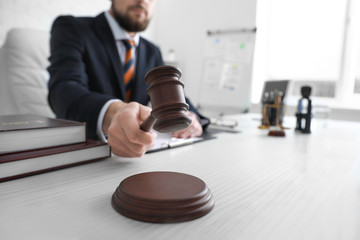 Male lawyer with judge gavel sitting at workplace in office