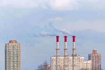Pipes of industrial factory. Smoke, air emissions from an industrial pipe on a blue sky background/...