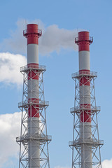 Pipes of industrial factory. Smoke, air emissions from an industrial pipe on a blue sky background/ The smoke from the chimneys against the blue sky