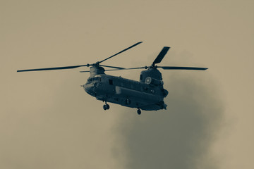 Military combat and war with Chinook helicopter flying through the chaos and destruction. Smoke and...