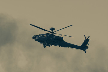 Military chopper close up in war flies through the smoky hazy sky in combat. Military concept of power, force, strength, air raid.