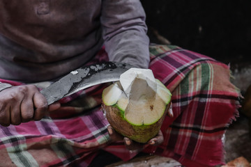 Man cutting coconut with knife