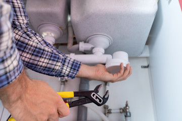 Male Plumber Fixing Sink In Bathroom