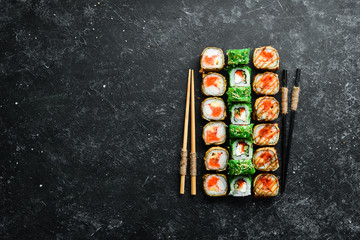 Big set of sushi rolls with seafood on a black stone background. Top view. Free space for your text.