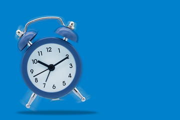 Classic alarm clock ringing isolated on blue background.