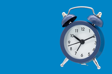 Classic alarm clock isolated on blue background.
