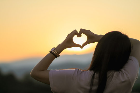 An Asian woman shows a heart symbol to tell her lover on Valentine's Day and the symbol showing love and friendship that has always been.