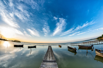 Beautiful morning landscape with boats on the lake anchored to the pier and wood bridges at sunrise, Razelm Razim Lake, Sarichioi, Romania