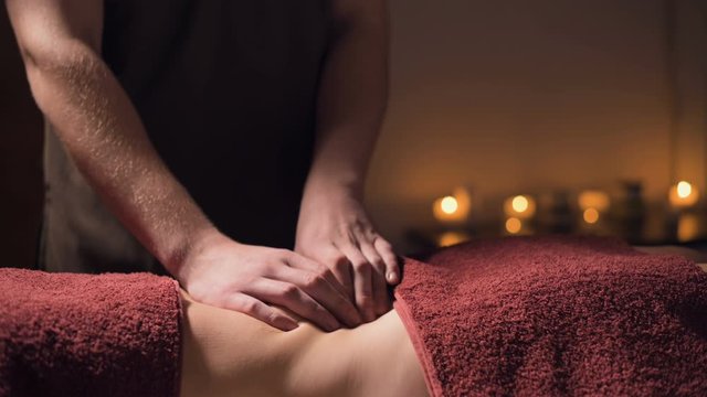 Medium shot shallow depth of field. Professional elite massage of the abdomen anti-cellulite and useful for internal organs in a dark massage room