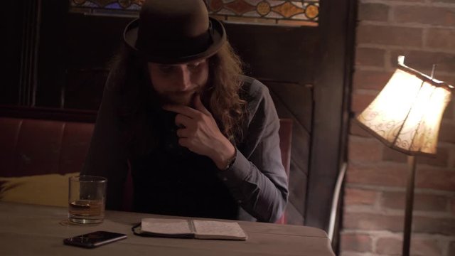 Writer / Philsopher ihas no idea what to write. He is drinking whiskey instead of working. He looks thoughtful.