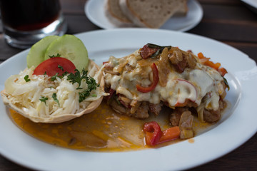 Close up of baked schnitzel meat with mushrooms and sauce on white plate