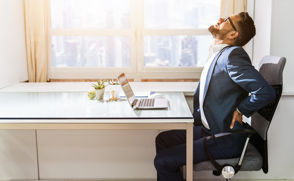 Businessman Sitting On Chair Suffering From Back Pain