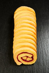 slice of festive sponge roll with jam on a wooden background