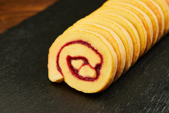 slice of festive sponge roll with jam on a wooden background