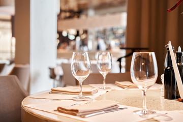 Wine glasses in the foreground. The chairs and table for guests, served with cutlery and crockery