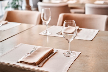 Wine glasses in the foreground. The chairs and table for guests, served with cutlery and crockery