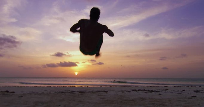 Muscular african capoeira acrobatic athlete is performing tricks on a desert sea water with splash on a sunset. Concept: healthy lifestyle, diet, wellbeing, fitness, proper nutrition, love for sports