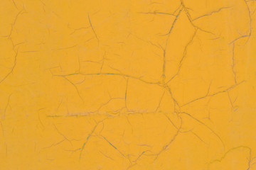 Yellow painted wall with cracks. Texture, background. Fragment of a wall painted with oil paint. The paint is cracked.