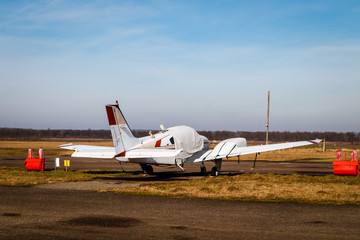 A small plane stands in the parking lot of an old airfield. Wings. Airport. Airfield. Flights by plane.