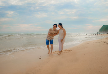 Fototapeta na wymiar romantic lifestyle portrait of young Asian Korean couple in love enjoying holiday on beautiful beach walking together by the sea playful and carefree in happy relationship