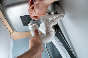 Male Plumber Fixing Sink In Kitchen