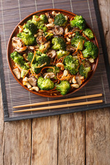 Chinese fried shiitake mushrooms, broccoli, carrots and cashew nuts close-up in a plate. Vertical top view