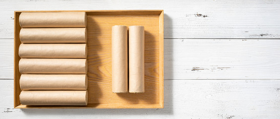Some moxa sticks are in rectangular wooden trays. A wooden tray with 8 moxa sticks is placed on a white table top.