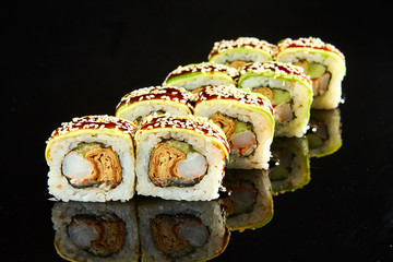 Traditional sushi roll with shrimps, cream cheese and egg omlet on black stone. Japanese food
