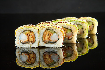 Traditional sushi roll with shrimps, cream cheese and egg omlet on black stone. Japanese food