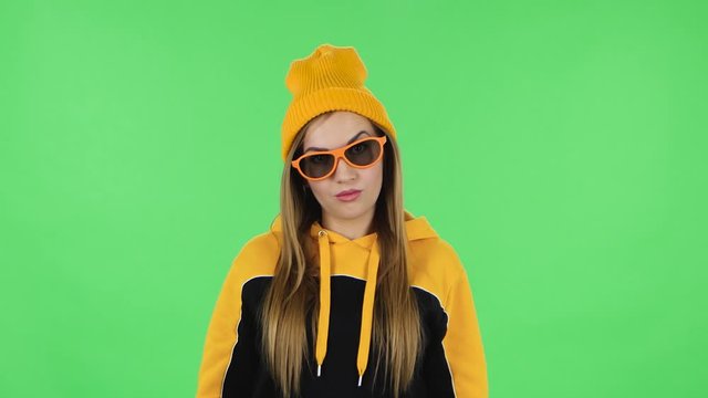 Portrait frustrated girl in yellow hat is taking off sunglasses and saying wow with shocked face expression. Greenscreen