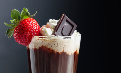 Chocolate drink with whipped cream, strawberry and pieces of black chocolate.