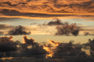 Aerial view of beautiful clouds over Pacific ocean lit by low evening sun 