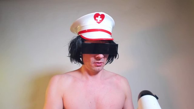A transgender man in a white cap shouts into a megaphone at a kinky party. LGBT concept.