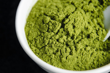 Matcha green tea powder in a white bowl, texture close up. Selective focus