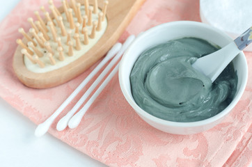 Blue bentonite clay in a bowl, wooden hairbrush and cotton swabs. Diy facial mask and body wrap recipe. Natural beauty treatment and spa. Copy space.