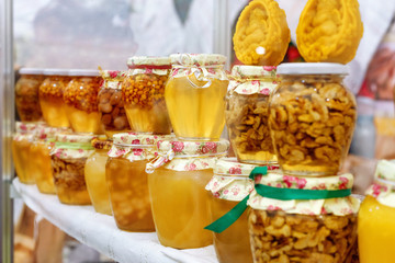 Assortment of honey jars at market stall. Sale of natural honey in fair outdoor.