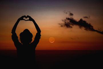 Silhouette of a girl holding heart-shape symbol for love on a starry night sky. My astronomy work.