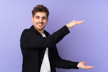 Caucasian man isolated on purple background holding copyspace to insert an ad