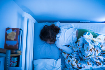 Small 11 year old girl sleeping in bed on a stomach.