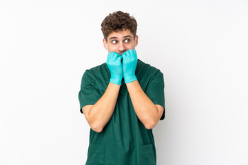 Surgeon in green uniform isolated on isolated white background nervous and scared putting hands to mouth