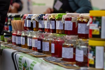 Beervelde/Belgium - October 13 2019: A bunch of freshly made pots of jam. The jars are colorful due to the homegrown fruit. The glass pots are stacked in rows and displayed at a local market.