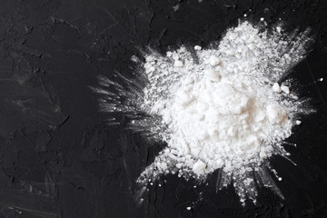 Corn starch on a black background, top view, copy space. Corn white starch on a black table. Potato starch on a black background. Top view, copy space.