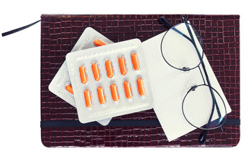 Medical pills pack with glasses and notepad for recipe. Healthcare notes and readings. Top view, isolated on white.