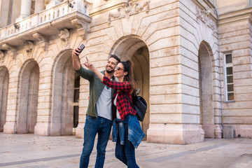 Fototapeta na wymiar A happy couple taking a selfie in while sightseeing ion a European city