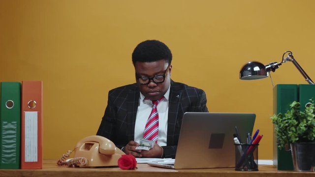 Successful black afro businessman financial manager takes bunch of money counting salary payday advance sitting at desk in his office corporation. Concept of career.