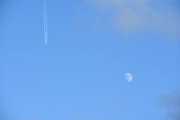 Airplane leaving a trail on a beautiful blue sky and full moon